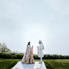 The serene moment of the varmala exchange during an outdoor ceremony, with the sky and landscape creating a stunning natural backdrop.
