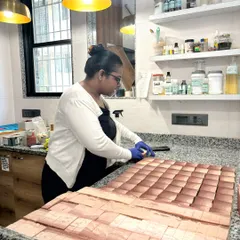 A candid shot of me at work, cutting a large slab of soap into individual bars. This multi-bar cutter is a lifesaver for efficiency, but it's still operated by hand with a lot of care.
