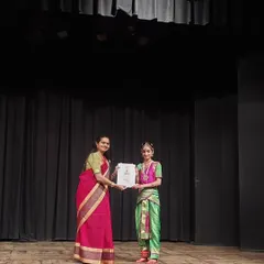 A proud moment for me, presenting a certificate of achievement to a graceful young performer on stage. I believe in recognizing every student's progress because every step on this journey counts.