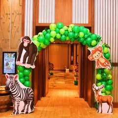 An entrance arch for a jungle party, decorated with bright green balloons and large animal cutouts like a zebra and monkey.