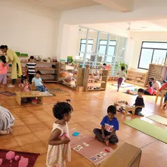 A wide view of our classroom during the work cycle. You can see multiple children working independently on different activities, from sensorial work on the floor to table activities, showcasing the freedom and focus our environment fosters.