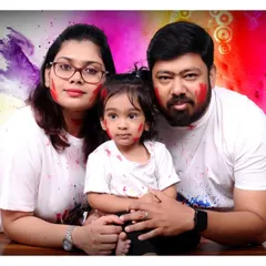 A close-up family portrait from a Holi session with a colorful, abstract background. I ensure the experience is fun for everyone, including the little ones.