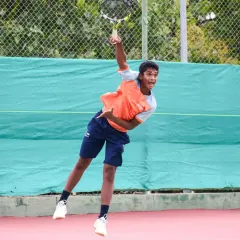 A young tennis player executes a powerful serve, capturing the explosive energy and technical precision we instill in our athletes through our high-performance tennis program.