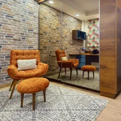 The den at Rue 32, a versatile space reimagined from a walk-in closet. It combines a home office, reading nook, and storage, featuring a cantilevered workstation, exposed brick, and a comfortable lounge chair to create a handcrafted masterpiece of space and solace.