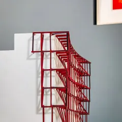 A conceptual study model of a curved metal exoskeleton. This red-painted model was an early exploration of a structural idea for a facade, testing its geometric complexity and visual impact.