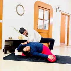 Achieving deep flexibility requires patience, trust, and expert guidance. Here, I am assisting a client in a reclining hero pose variation, focusing on safely opening the hips and shoulders. My hands-on approach ensures you can explore your body's limits without risk of injury, making advanced postures more accessible.