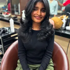 A happy client showcasing her new advanced layer haircut with a face-framing fringe. The style is finished with a perfect blow-dry that adds volume and enhances the layers.