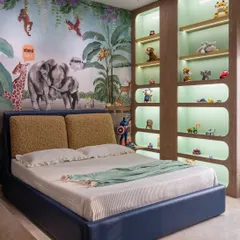 The centerpiece of this jungle-themed room is the bed set against a lively animal mural. We added custom-lit, curved shelving to display a collection of toys, making storage a fun and integral part of the design.
