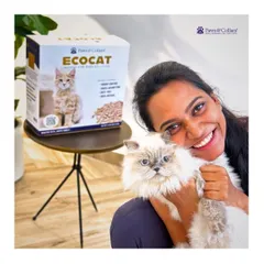A happy pet parent cuddles her cat next to a box of EcoCat litter. This image captures the satisfaction of finding a sustainable, high-quality product that works for both pet and owner.