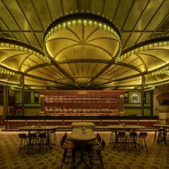 The main bar area at night, with the custom lighting creating a warm, inviting atmosphere. The patterned floor tiles and dark wood finishes contribute to the classic, sophisticated vibe of this restaurant interior.