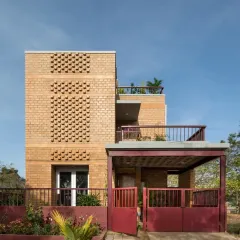 A closer view of the Eesha residence facade, highlighting the patterned brick jali screen. This feature provides ventilation and creates beautiful light play while adding a decorative element to the earth-block construction.