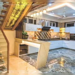 We designed this open-plan kitchen to be the heart of the home. It features a marble-finish floor, a functional breakfast counter, and custom cabinetry, all seamlessly integrated with the home's main staircase, which includes unique backlit onyx stone details.