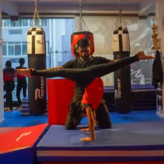 A coach assists a student with an advanced handstand variation, helping her find the point of balance. This one on one attention is key to mastering difficult strength and balance skills safely.