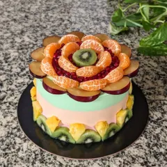 Another view of the fresh fruit cake, showing the vibrant colors of the plums, oranges, and kiwis. This is a delicious and healthy way to decorate a cake.