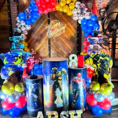 An action-packed Transformer theme for an 8th birthday. The decor features a balloon arch in primary colors and pedestals wrapped with images of the robot characters.
