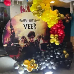A magical Harry Potter theme for a fan's birthday. This decoration includes a custom circular backdrop with the movie poster, and a balloon garland in Gryffindor colors of red, yellow, and black.