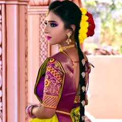 This profile shot highlights a traditional long braid decorated with jasmine and colored flowers. This type of hairstyling is an essential part of the complete South Indian bridal look.