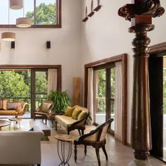 In the living room of the Dream Coffee Estate, a reclaimed antique wooden column stands as a silent witness to time, grounding the double-height space. We designed this room to be a conversation between old and new, where hand-chiseled stone floors and modern furnishings coexist under the expansive canopy of the Coorg forest visible through large glass doors.