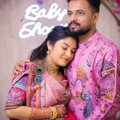For their baby shower, this couple chose a vibrant, coordinated look. The father-to-be is wearing a custom-printed pink kurta that matches the intricate details and colors of the mother-to-be's traditional saree.