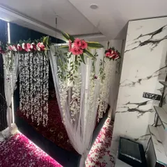 A beautiful floral decoration for a wedding night, with a canopy of flowers, sheer drapes, and a floor covered in rose petals.