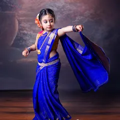 A stunning portrait of a young girl in a vibrant blue saree. Her dynamic pose and the graceful flow of the fabric create a beautiful and elegant image.