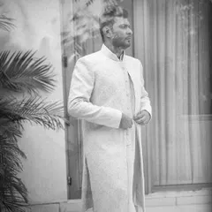A thoughtful black and white portrait of the groom, captured through a reflection for an artistic effect.