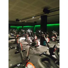 A full view of the spinning studio setup, showing the arrangement of bikes for optimal instructor visibility and class flow. The acoustic ceiling panels were installed to manage sound in the high-energy environment.