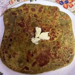 A healthy and delicious Palak Paratha, generously topped with homemade white butter. The paratha is made with fresh spinach puree mixed into the dough.