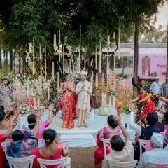 A moment of blessing and celebration as guests shower the couple with flowers and rice during their outdoor Maharashtrian wedding ceremony.