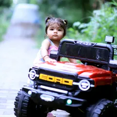 Here is Vaanya posing with her red toy jeep on a quiet park pathway. This shot establishes the fun theme of her first birthday photoshoot and shows how I compose wider shots that include the environment.