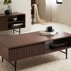 A styled shot of the coffee table from the collection, showing its storage capabilities and sleek design. The focus is on both aesthetics and functionality.