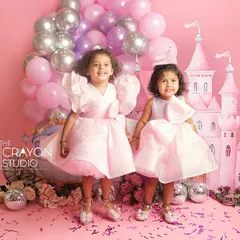 Two little princesses, hand in hand in front of their fairytale castle. This themed kids portrait is a beautiful memory of sisterhood and the magic of childhood imagination.