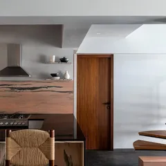 A glimpse of the "flying" treads of the staircase next to the kitchen. The dramatic pink marble backsplash adds a bold stroke of color and natural pattern to the space.