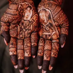 A close up of a bridal design featuring portraits of Radha and Krishna. Incorporating spiritual figures is a beautiful way to add a layer of divine blessing and personal faith to your wedding henna.