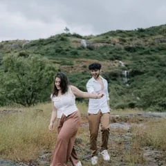 Leading the way on a mountain path. This candid shot captures the couple's playful energy and connection as they explore the natural scenery together during their pre-wedding adventure.