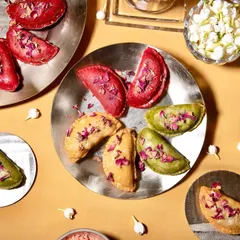 Savor the sweetness of my baked gujiyas, available in different natural colors like beetroot red and spinach green. They are filled with a moist dry fruit mixture and are a modern take on a classic.