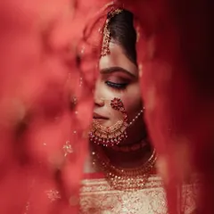 A bridal portrait is more than a photo; it's a story. Here, we created an artistic and intimate moment with our bride Kriti, using her vibrant red veil to frame her serene expression just before the ceremony began.