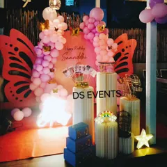 This enchanting butterfly-themed decoration features large, custom-made butterfly wings as a central backdrop element. The pink balloon garland and elegant ribbed plinths complete this beautiful setup for a magical birthday.