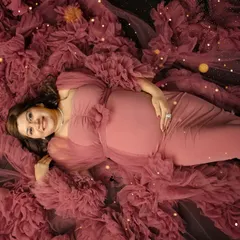 Lying in a bed of ruffled fabric, this mother-to-be looks so peaceful and happy. I use creative angles and lighting to add a touch of magic to these studio portraits.