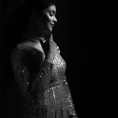 A timeless black and white portrait. The soft light catches the sparkle of her dress, while her gentle smile and pose convey a feeling of quiet happiness and grace.