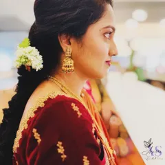 A side profile showcasing a traditional braided hairstyle adorned with fresh jasmine flowers. This classic look is perfect for a muhurtham ceremony, combining fragrance and beauty.