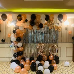 Celebrating a 20th birthday with a touch of class. This setup features a balloon arch in black, white, and rose gold, a silver fringe curtain, and large foil balloons for the number '20' and the word 'Love'.