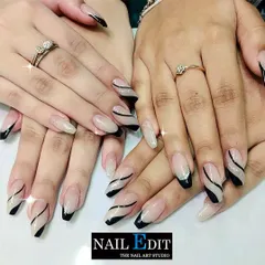 A stylish and graphic take on nail art, this set features a combination of black French tips and abstract black swirls on a sheer nude base. Some nails are accented with a glittery finish for added dimension.