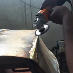 A behind-the-scenes look at our workshop, where a craftsman is carefully grinding and shaping a bent brass sheet. This is part of the process for creating a custom furniture piece.