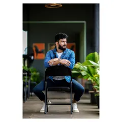 An indoor portrait with a modern, architectural feel. The model's strong pose and the clean lines of the background create a sharp, contemporary image perfect for a men's fashion lookbook.