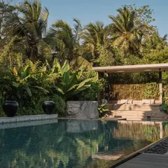 The poolside at GAIA, where we used large, dark urns as sculptural elements against the backdrop of a tropical garden. The design creates a serene, resort-like atmosphere.