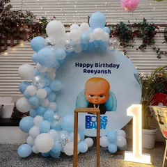 Who's the boss? This Boss Baby themed first birthday party features a custom backdrop with the character, a blue and white balloon arch, and a light-up number '1'.