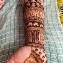 This design features a band of marching elephants, a classic element in bridal mehendi. Above it, you can see lotus and peacock motifs.