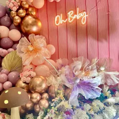 A close-up of the intricate details in the enchanted garden theme. You can see the sheer fabric flowers, small floral bunches, and a variety of balloon sizes and finishes that add depth and elegance.