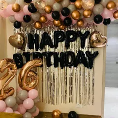 A stylish 26th birthday backdrop featuring a silver sequin curtain, a black "Happy Birthday" sign, and a balloon garland in pink, black, and rose gold.